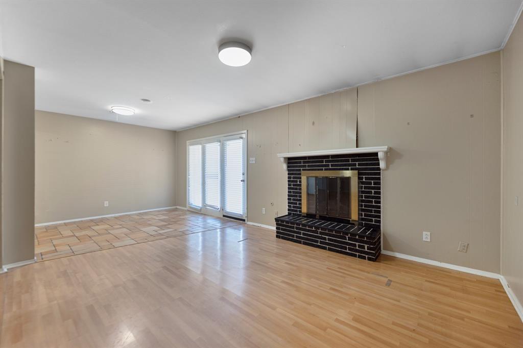 518 Worcester Way Richardson, TX 75080 - Photo 9 of 35 an empty room with wooden floor a fireplace and windows