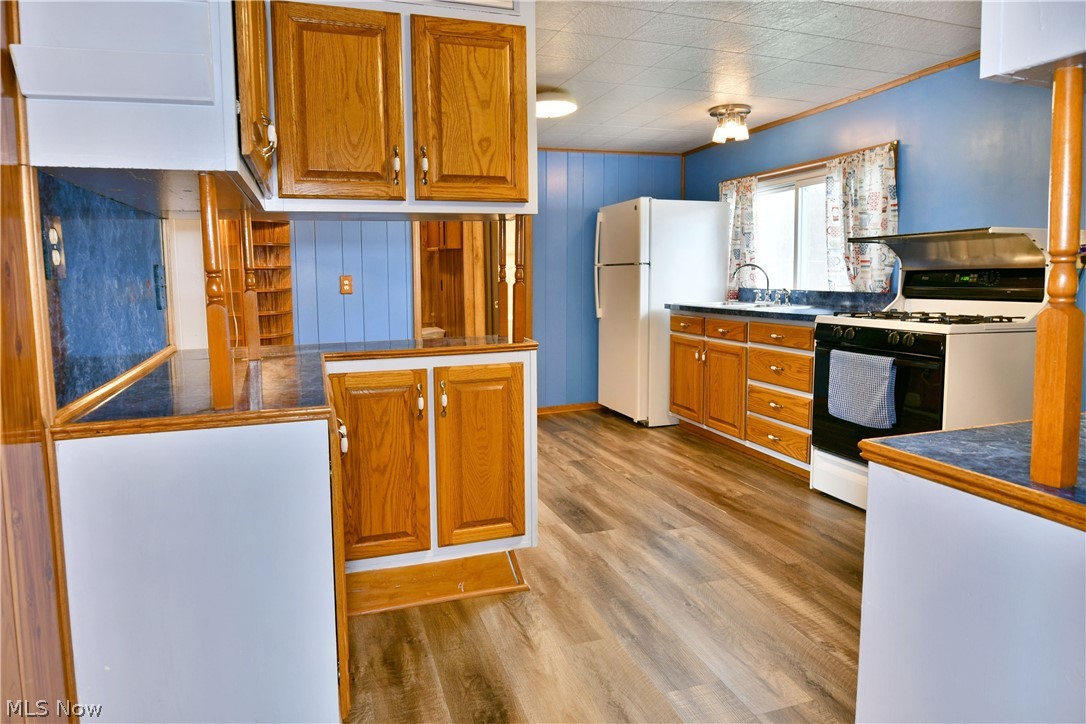 878 Ridge Road Vienna, OH 44473 - Photo 21 of 50 Kitchen with wood finish cabinetry, white appliances, dark countertops, and light wood-style floors