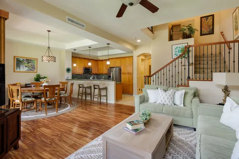 a living room with furniture kitchen view and a wooden floor