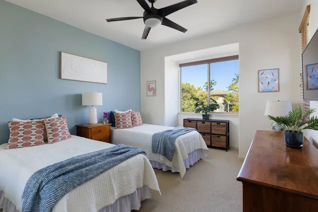 a bedroom with two beds and a potted plant