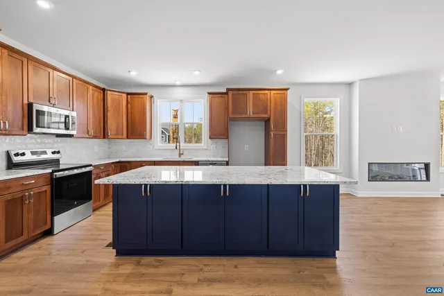 a kitchen with stainless steel appliances granite countertop a refrigerator a sink dishwasher a stove and a oven with wooden floor