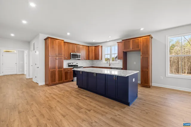 a kitchen with stainless steel appliances granite countertop a refrigerator a sink dishwasher a stove and white countertops with wooden floor