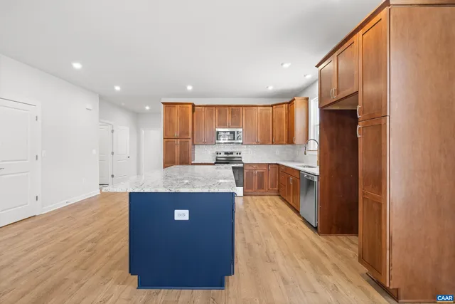 a kitchen with kitchen island granite countertop wooden cabinets a refrigerator and a sink