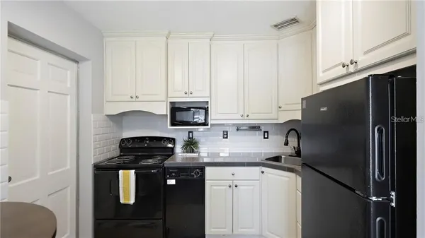 a kitchen with granite countertop a refrigerator sink and cabinets