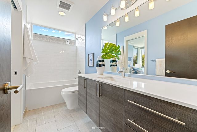 a spacious bathroom with a granite countertop sink a toilet a mirror and shower