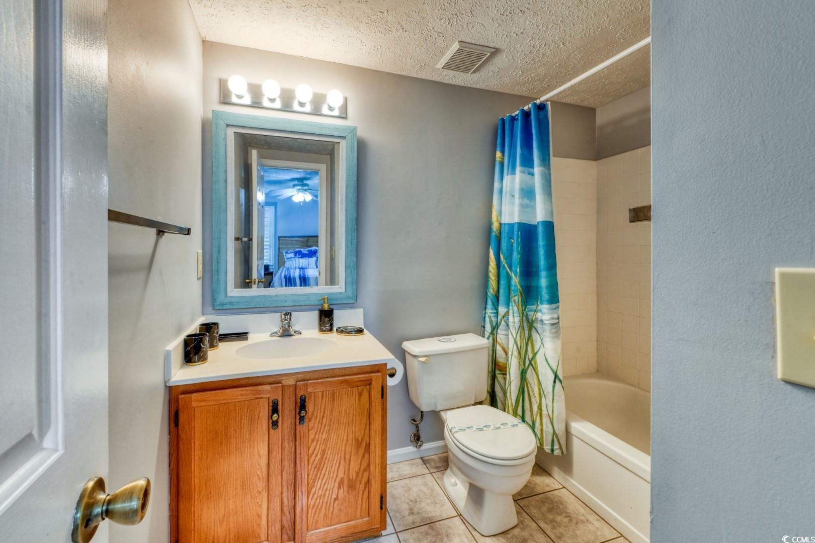 3714 Jordan Landing Road Murrells Inlet, SC 29576 - Photo 14 of 39 Full bath with shower / bath combo with shower curtain, a textured ceiling, vanity, and light tile patterned floors