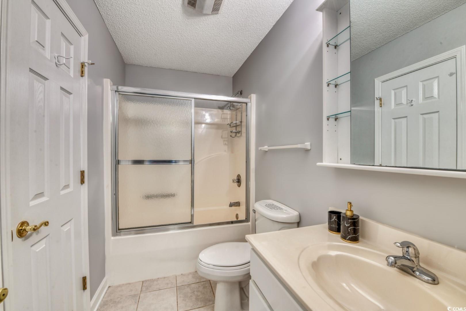 3714 Jordan Landing Road Murrells Inlet, SC 29576 - Photo 22 of 39 Full bath with shower / bath combination with glass door, a textured ceiling, vanity, and light tile patterned floors