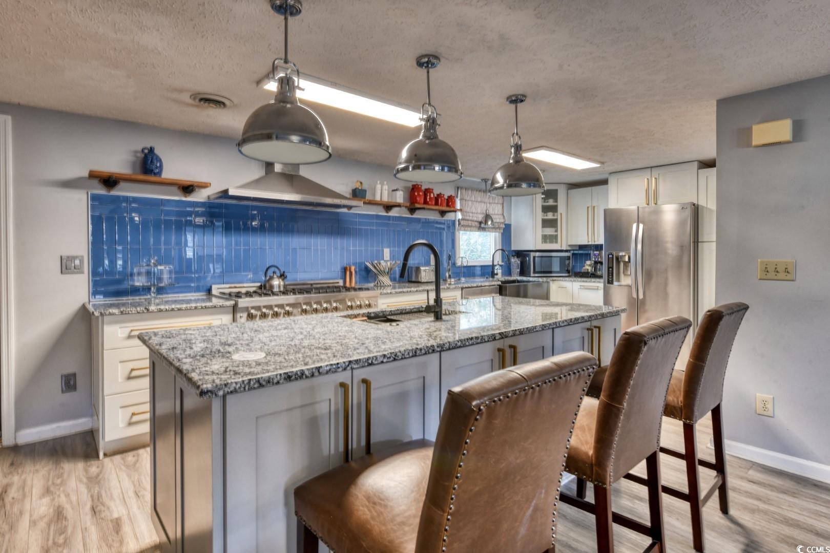 3714 Jordan Landing Road Murrells Inlet, SC 29576 - Photo 6 of 39 Kitchen with light stone countertops, white cabinetry, a textured ceiling, and appliances with stainless steel finishes