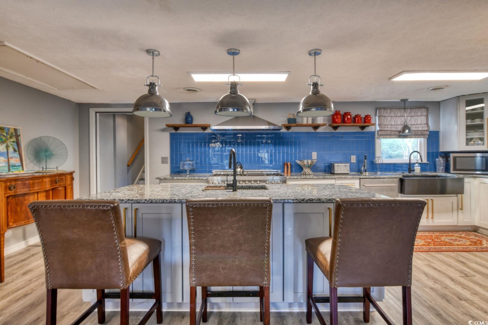 3714 Jordan Landing Road Murrells Inlet, SC 29576 - Photo 7 of 39 Kitchen featuring light wood-style flooring, pendant lighting, light stone countertops, and glass insert cabinets