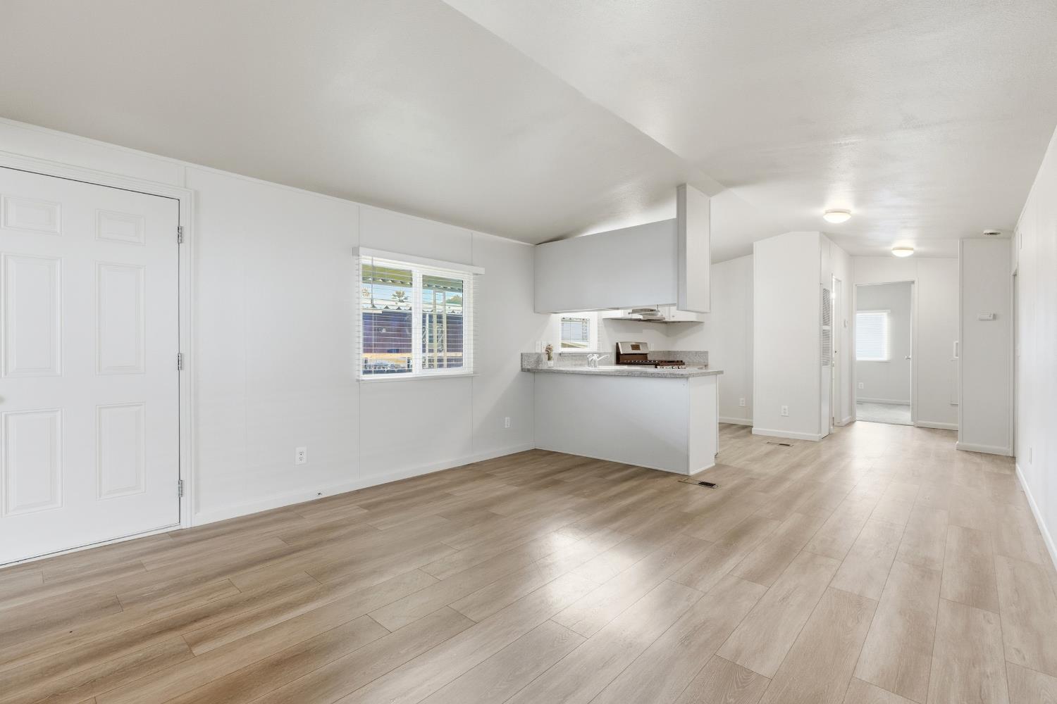 2307 Oakdale Road, Unit 15 Modesto, CA 95355 - Photo 6 of 17 an empty room with wooden floor kitchen view and a window