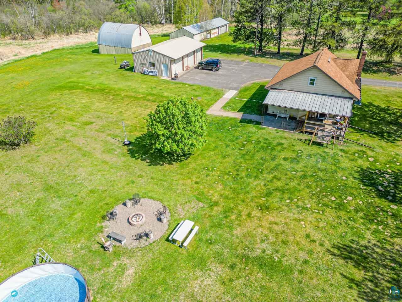 2581 O'Rourke Road Hibbing, MN 55746 - Photo 51 of 61 Expansive green space featuring a circular fire pit area with seating, a large above-ground pool, and a gravel driveway