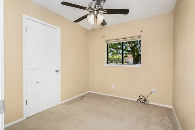 an empty room with windows and fan