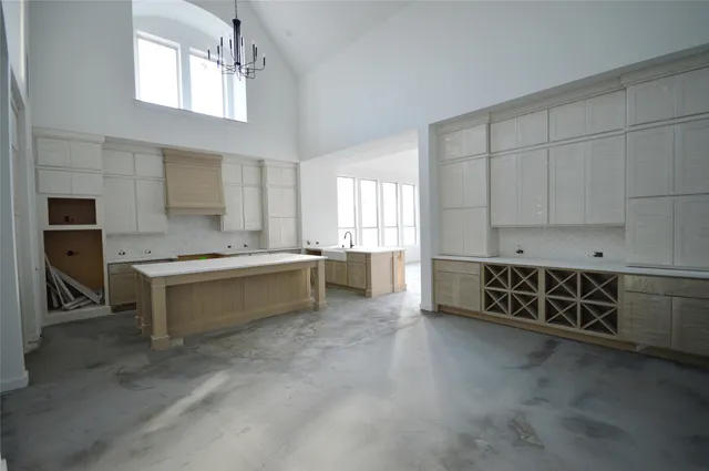 a large white kitchen with granite countertop a stove a sink a window and white cabinets