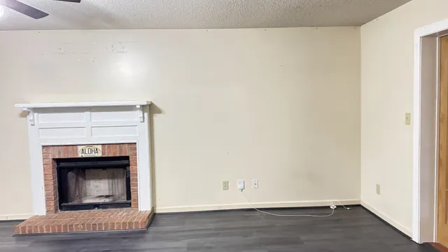 a view of an empty room with wooden floor and a fireplace
