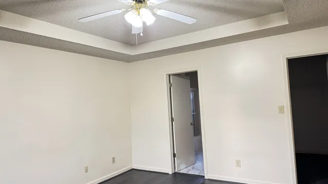 an empty room with wooden floor chandelier fan and entryway