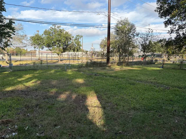 a view of a yard in front of a house with plants and large tree
