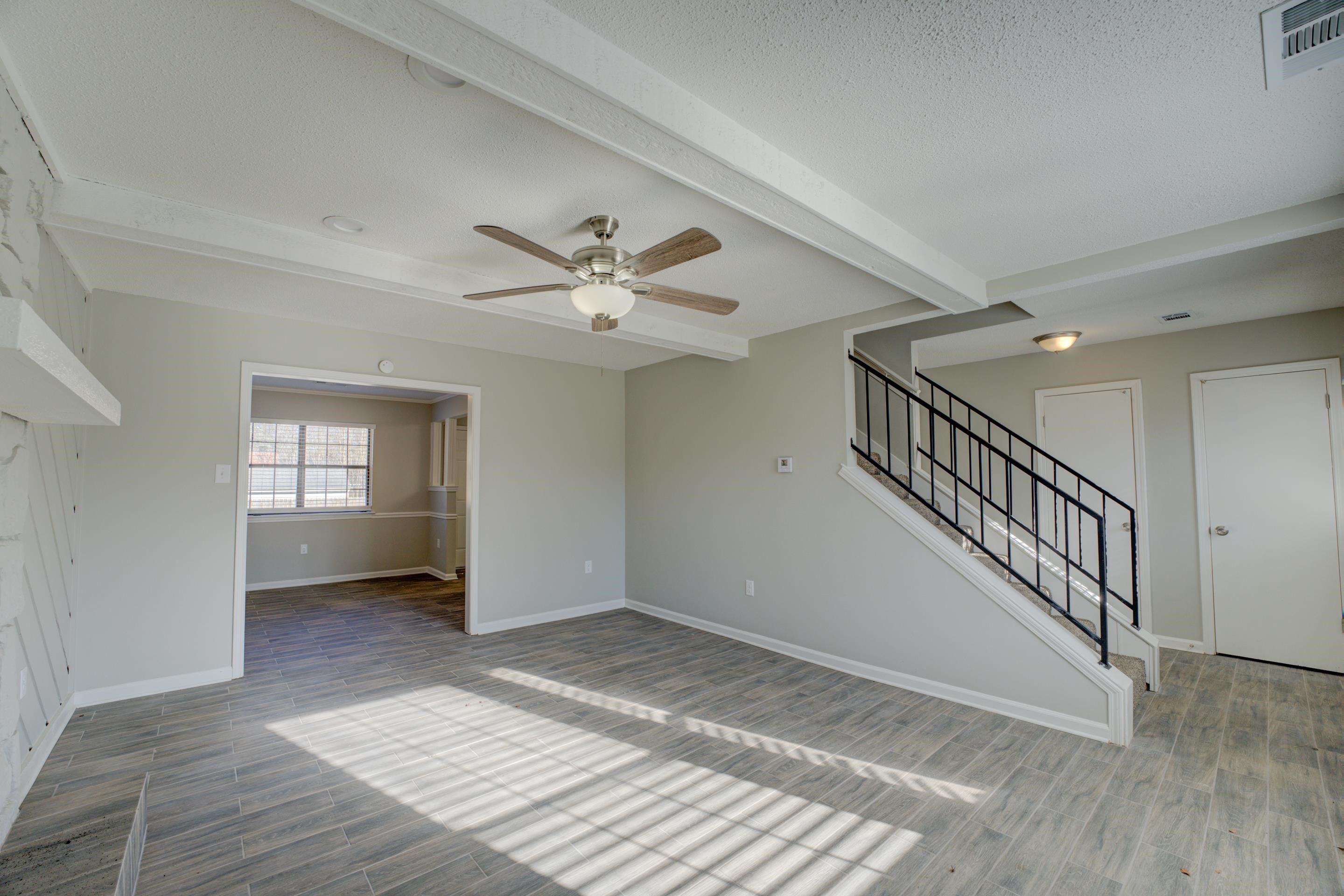 3808 Haynes Road Bartlett, TN 38133 - Photo 11 of 24 Unfurnished living room with beam ceiling, ceiling fan, wood-type flooring, and a textured ceiling