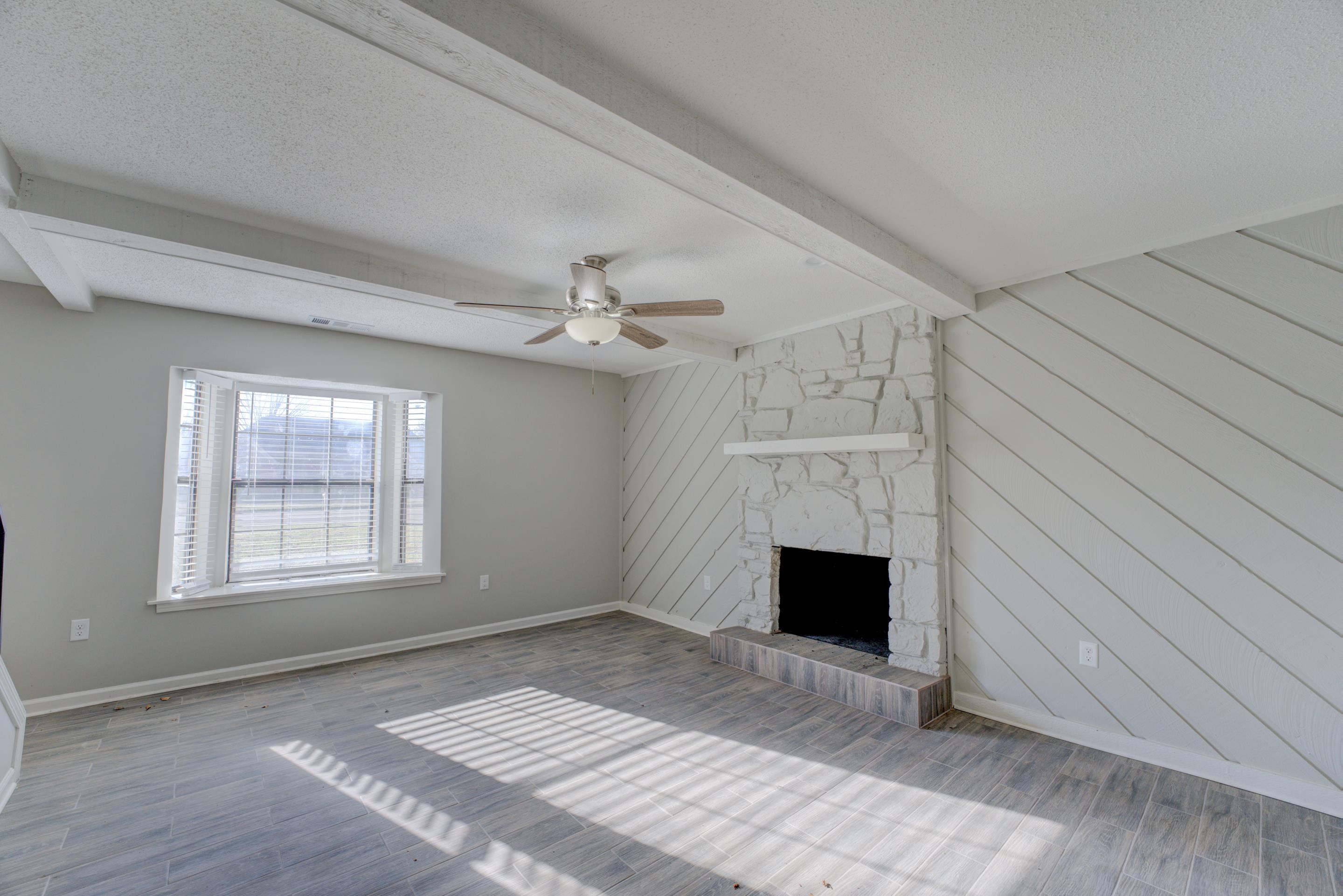 3808 Haynes Road Bartlett, TN 38133 - Photo 9 of 24 Unfurnished living room with a fireplace, beamed ceiling, a textured ceiling, and wood-type flooring