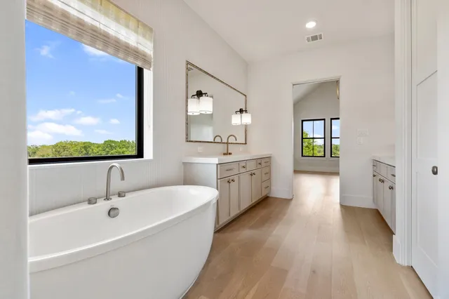 a bathroom with a double vanity sink a mirror and a bathtub