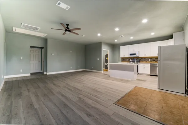 an open kitchen with kitchen island wooden floors appliances and cabinets