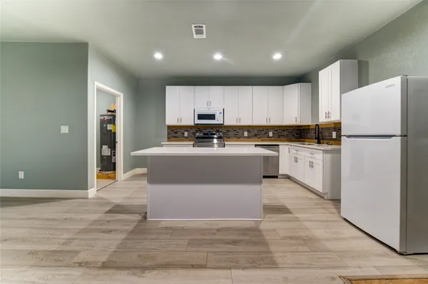 a kitchen with a refrigerator a stove top oven and white cabinets