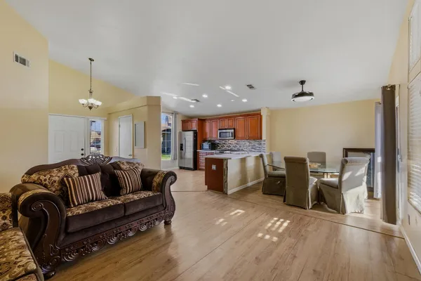 a living room with furniture kitchen view and a chandelier