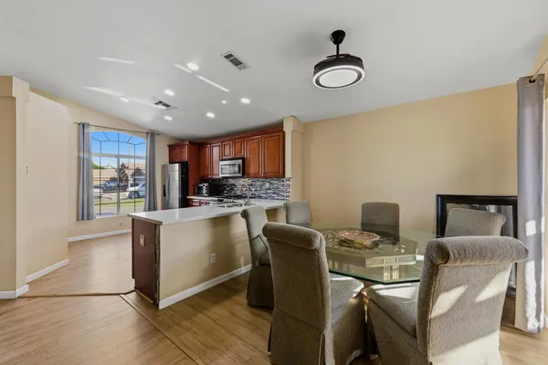 a kitchen with stainless steel appliances granite countertop a stove top oven a sink dishwasher a dining table and chairs with wooden floor