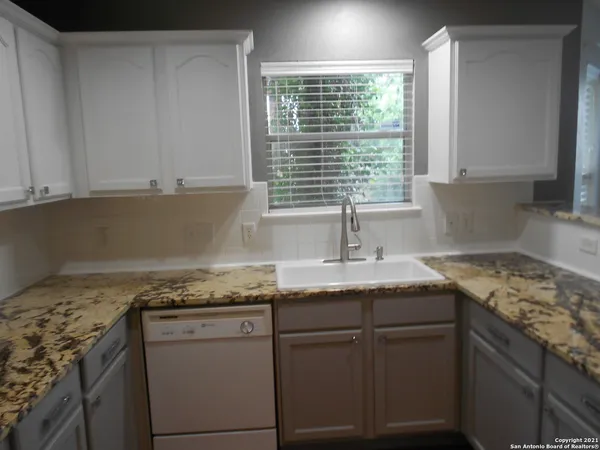 a kitchen with granite countertop cabinets sink and window