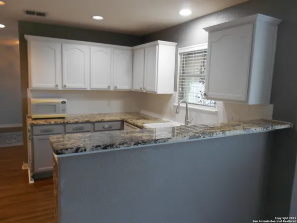 a kitchen with granite countertop a sink a stove and cabinets
