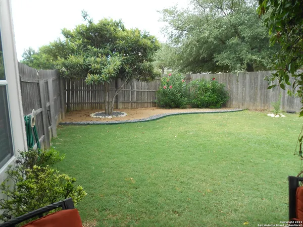a view of a backyard with large trees and wooden fence