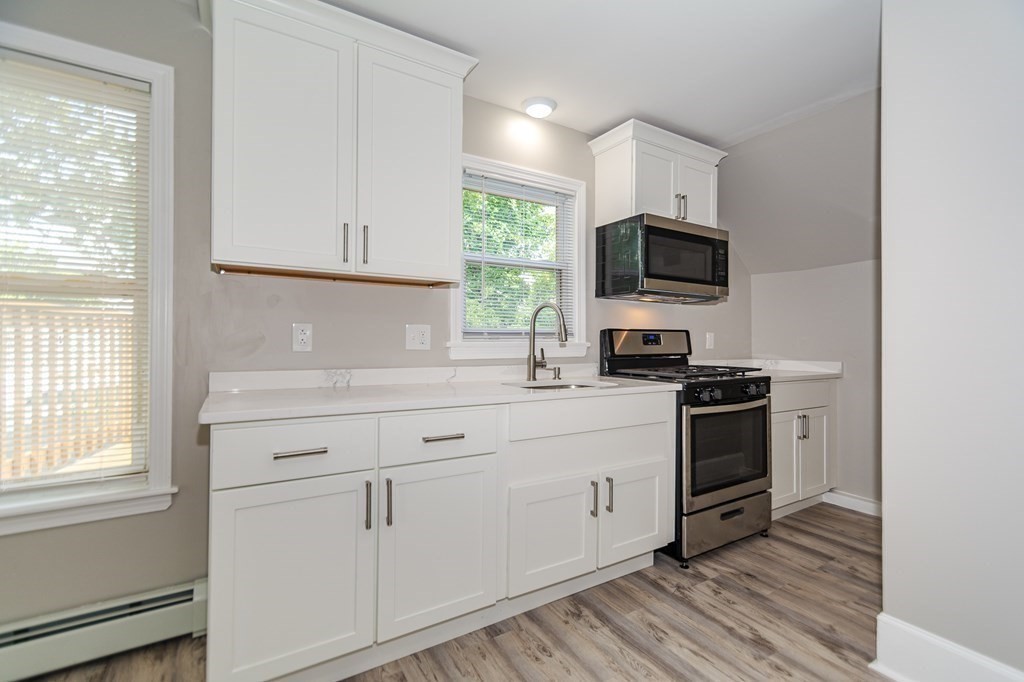 48 Washington Street Lawrence, MA 01841 - Photo 29 of 38 a kitchen with white cabinets stainless steel appliances and window
