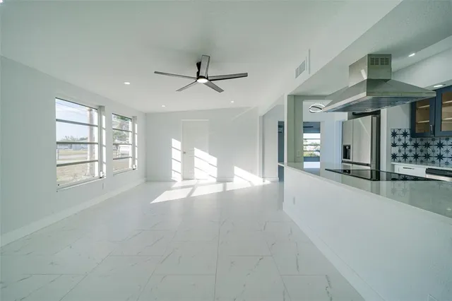 a living room with kitchen view and a ceiling fan