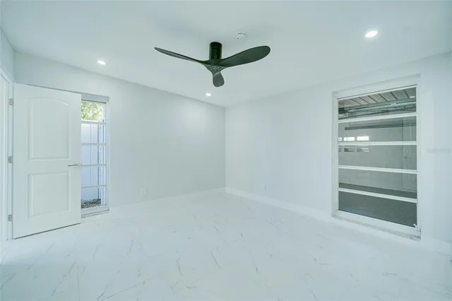 a view of an empty room with a ceiling fan and window