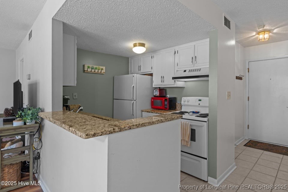 10 Pine Tree Road, Unit 211 Pinehurst, NC 28374 - Photo 21 of 36 a kitchen with refrigerator and cabinets