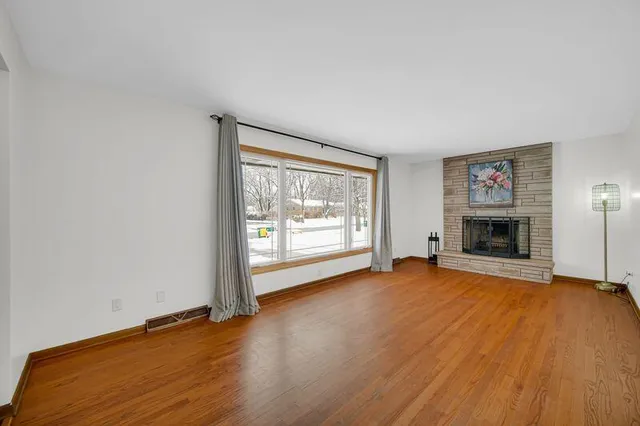 an empty room with wooden floor and fireplace