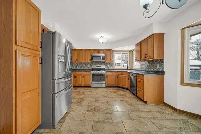 a kitchen with stainless steel appliances granite countertop a stove a sink a refrigerator and a microwave