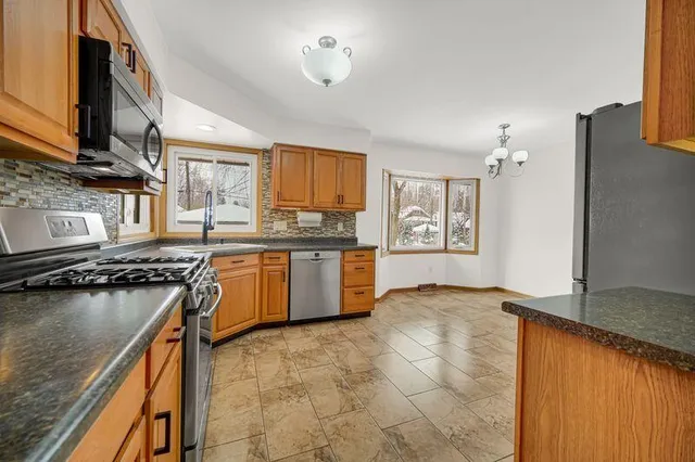 a kitchen with stainless steel appliances granite countertop a stove a sink dishwasher and a refrigerator