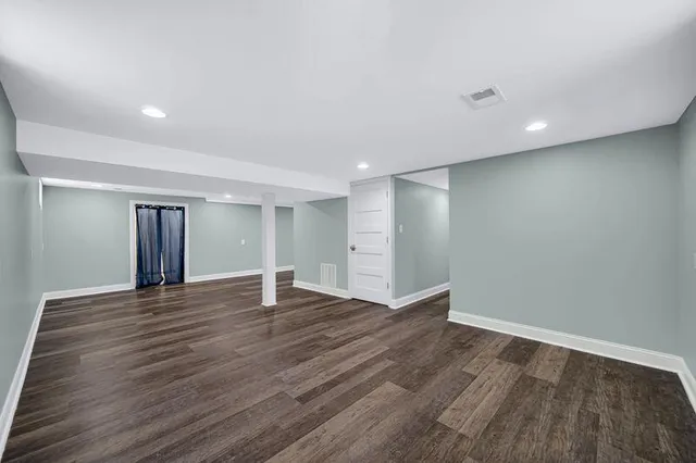a view of an empty room with wooden floor and window