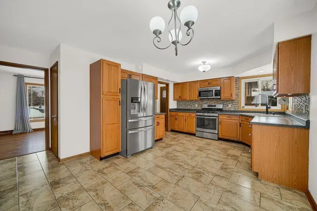 a kitchen with stainless steel appliances granite countertop a refrigerator a stove top oven a sink dishwasher a dining table and chairs