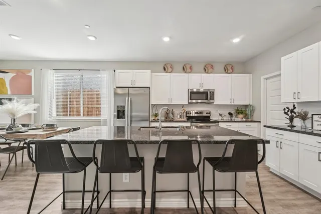 a kitchen with stainless steel appliances granite countertop a stove top oven a sink dishwasher and a refrigerator