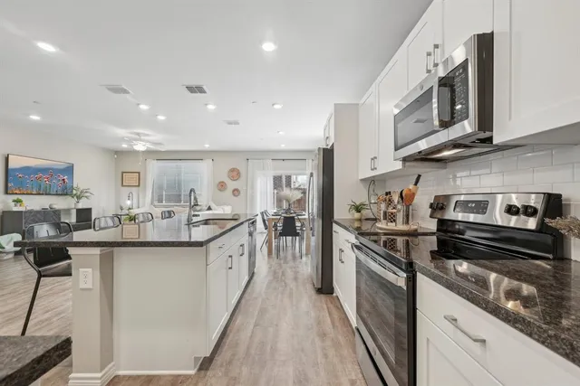 a kitchen with stainless steel appliances a dining table chairs refrigerator and microwave