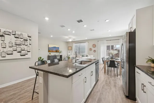 a kitchen with stainless steel appliances granite countertop white cabinets a stove a sink and dishwasher