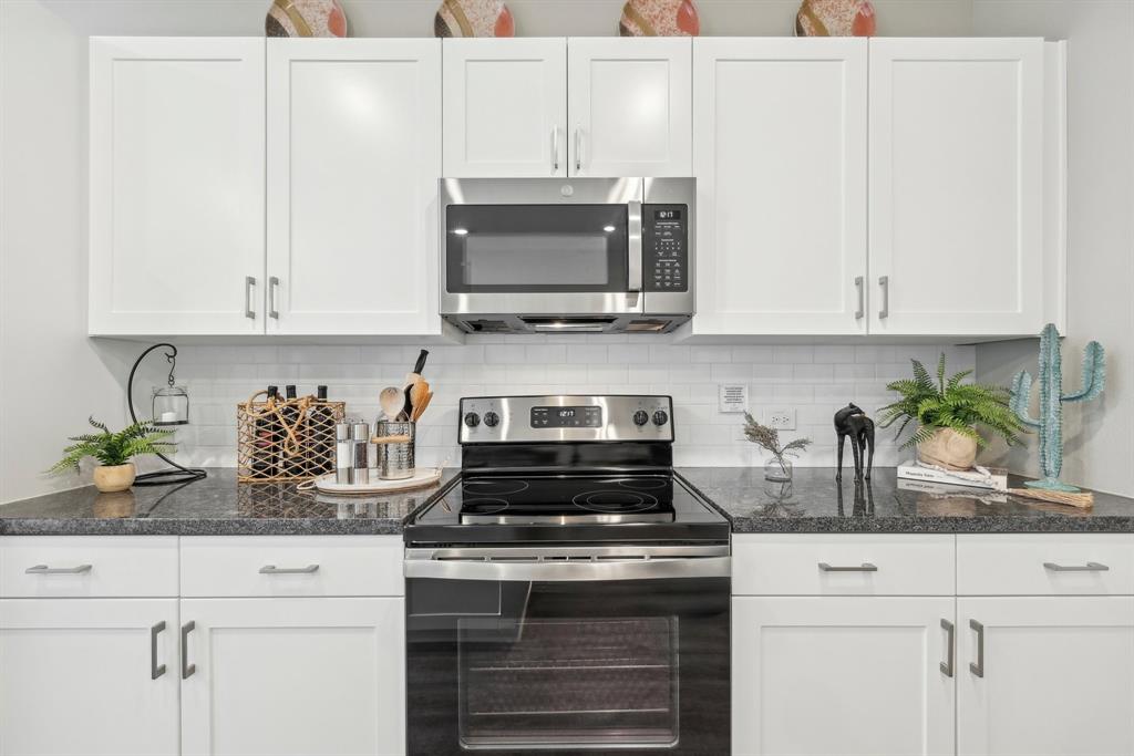 4430 Prairie Crossing, Unit 100 Prosper, TX 75078 - Photo 15 of 38 a kitchen with stainless steel appliances granite countertop white cabinets a stove a sink and dishwasher