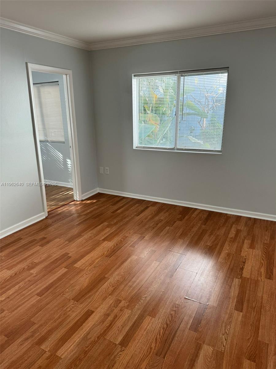 103 Northwest 6th Avenue, Unit 2 Miami, FL 33128 - Photo 17 of 20 a view of an empty room with wooden floor and a window