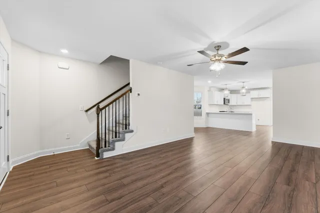 a view of an empty room with wooden floor and a kitchen