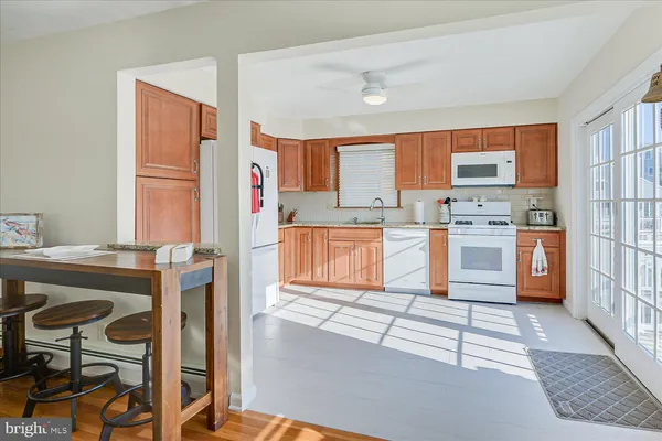 a kitchen with stainless steel appliances granite countertop a stove top oven a sink a dining table and chairs with wooden floor
