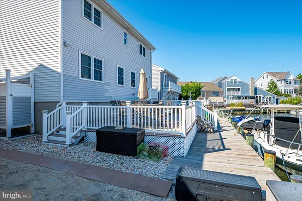 a view of a roof deck with table and chairs a barbeque with wooden floor and fence
