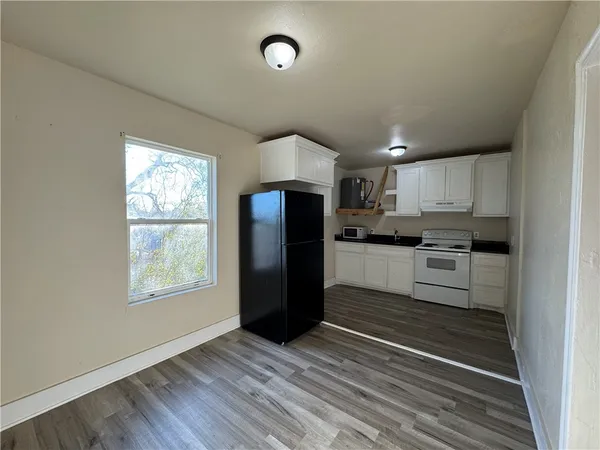 a kitchen with granite countertop a refrigerator and a stove top oven
