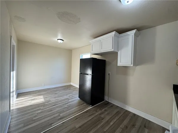 a view of an empty room with wooden floor and a cabinet