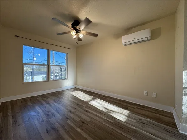 a view of an empty room with a window and wooden floor